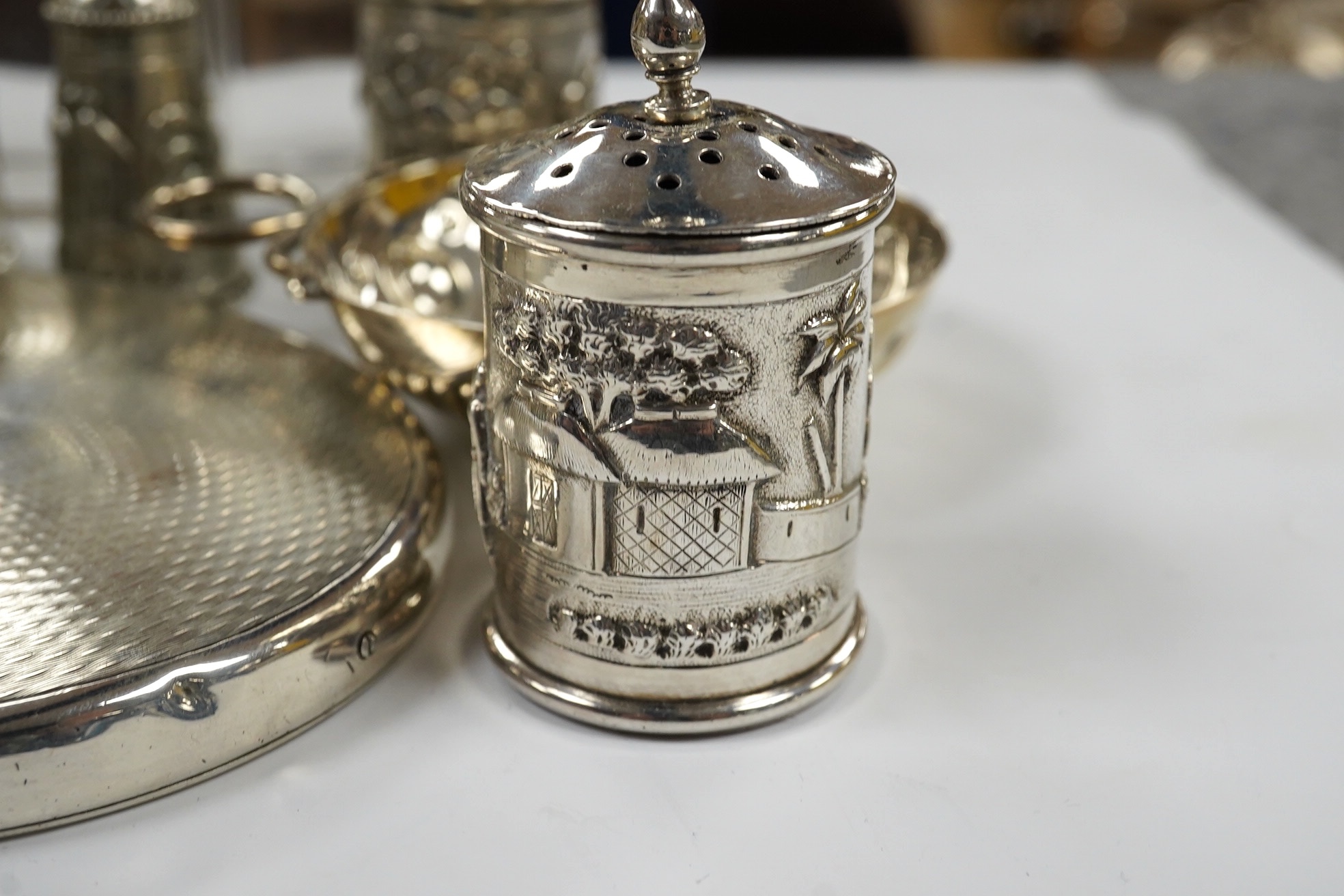 Small silver including a napkin ring, hand mirror and two mounted glass toilet jars, together with three Indian white metal condiments and a French white metal wine taster. Condition - poor to fair
